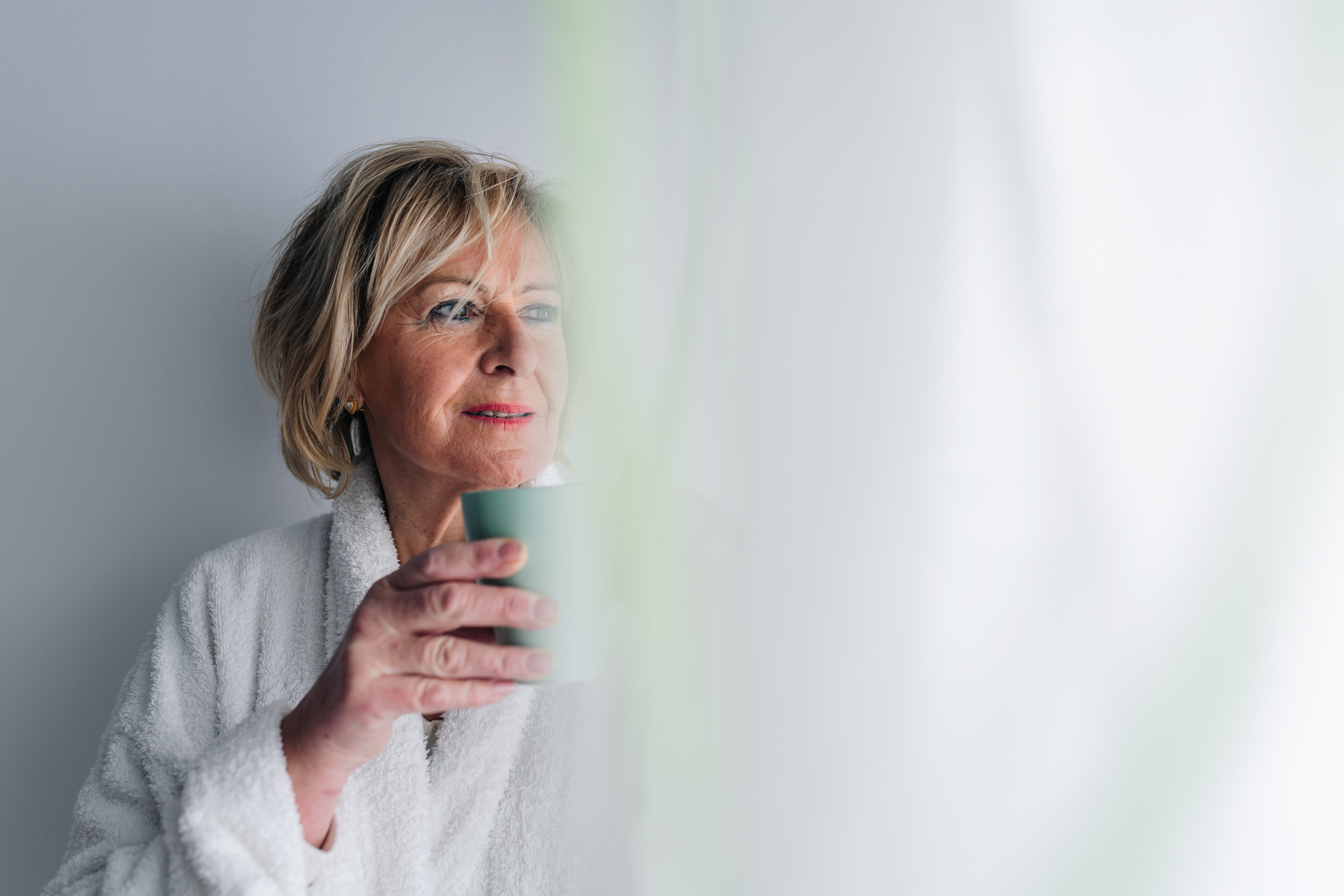 Mature Woman in a Bathrobe Holding a Coffee Cup